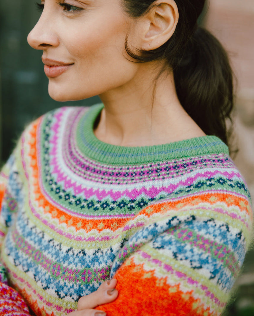 Woman wearing the Eribe Alpine Short Merino Sweater in Bella Rose orange