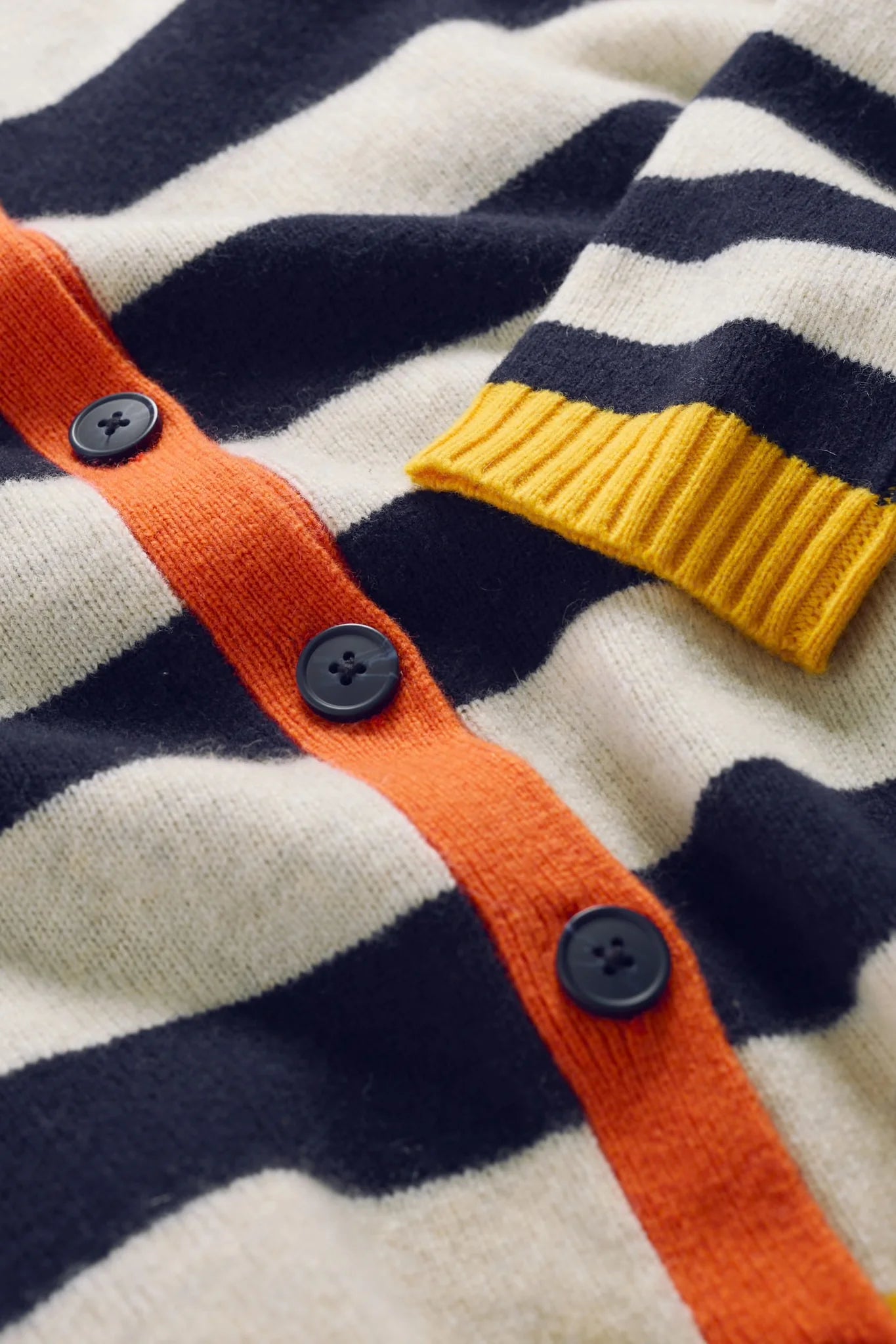 Close up of women's cardigan by SEASALT in striped navy, white, orange and yellow