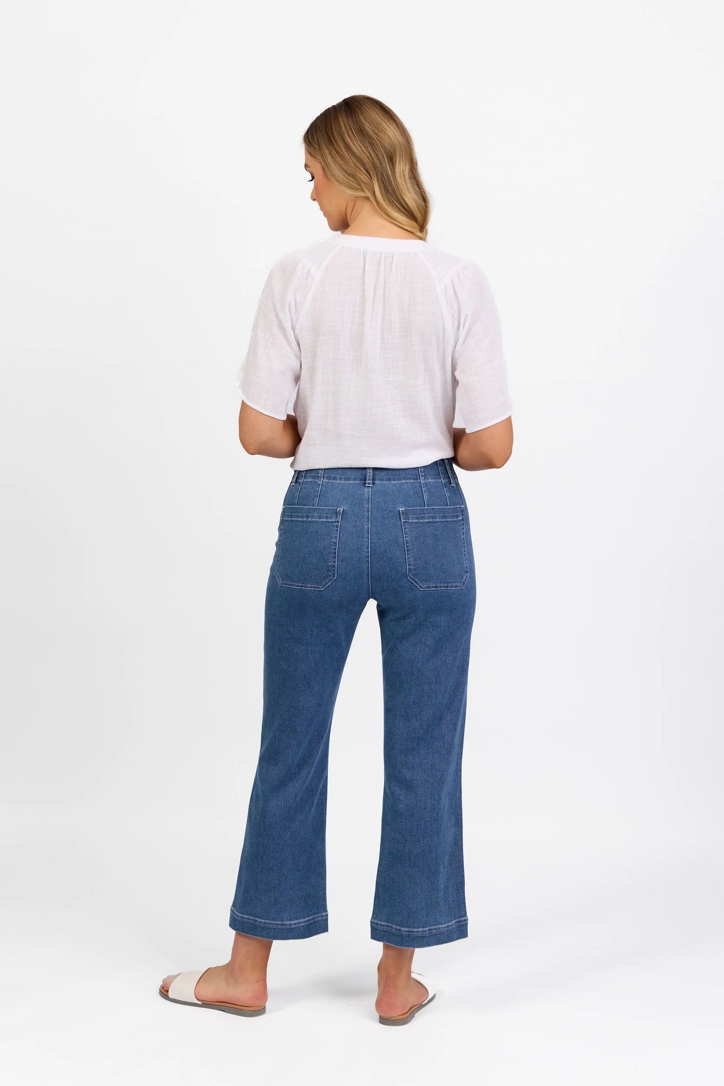 woman wearing the daily jean by vassalli- straight leg ankle grazer jean with front pockets in blue hue