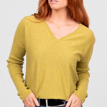 Woman wearing the Curved Hem Vee Neck Jumper in Citrine green by Bridge and Lord