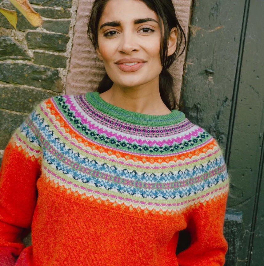 Woman wearing the Eribe Alpine Short Merino Sweater in Bella Rose orange