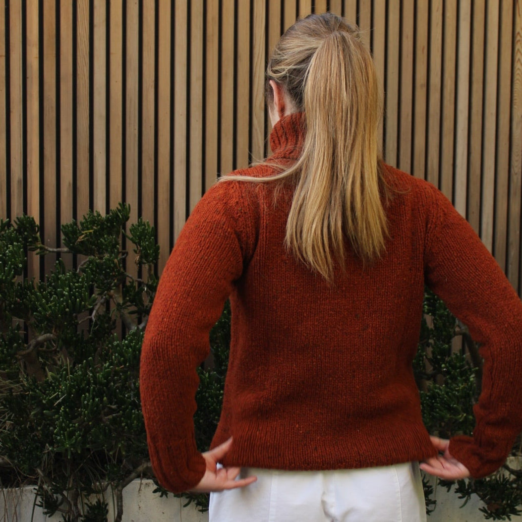 Woman wearing the Fisherman out of Ireland Turtleneck Saddle Jumper in Rust. Australian Merino wool.