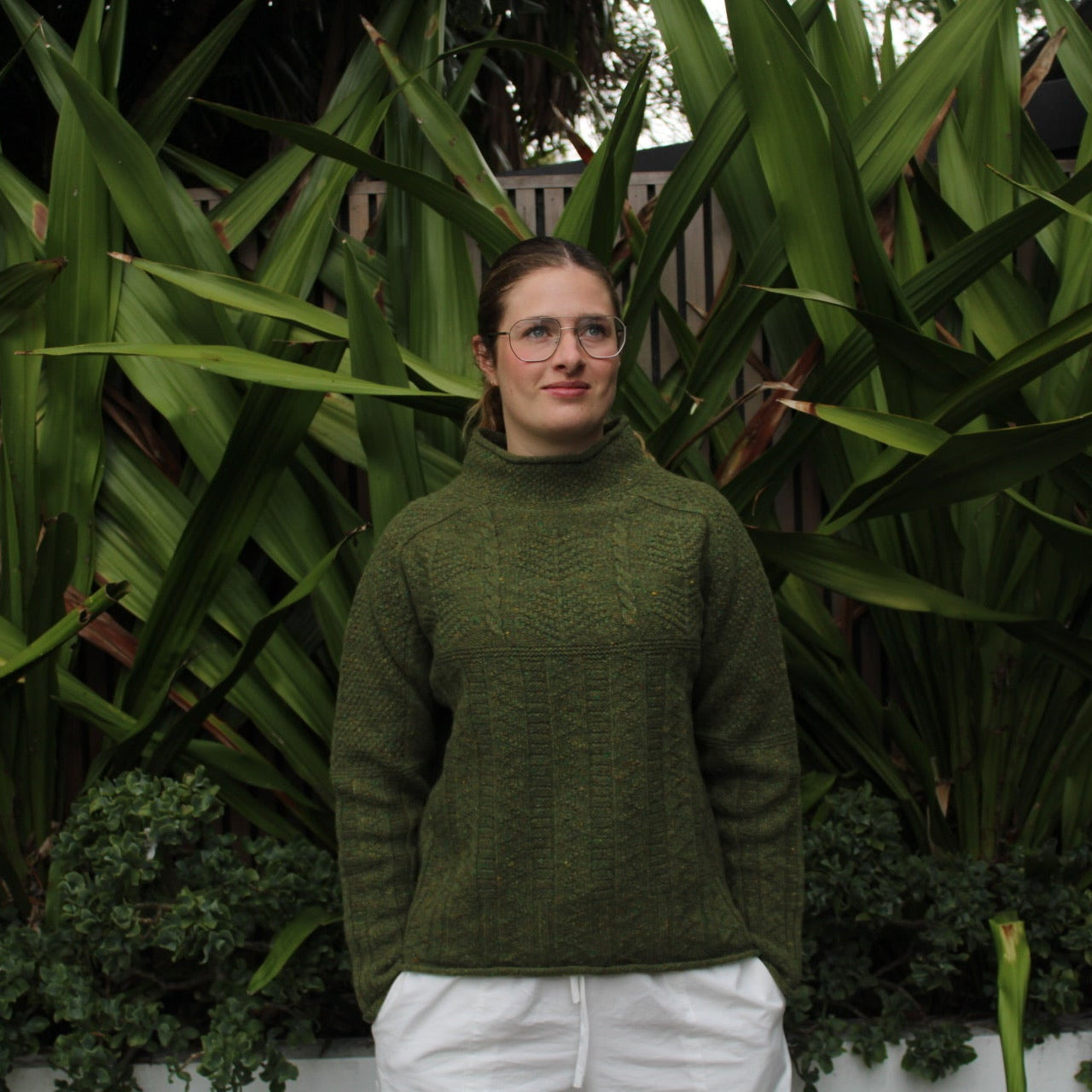 Woman wearing the Aran Tunic wool cable sweater by Harley of Scotland in Raasay green