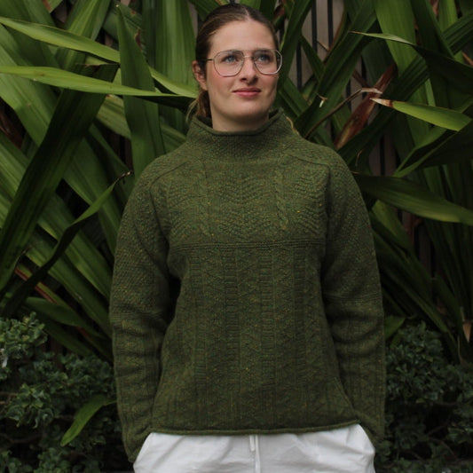 Woman wearing the Aran Tunic wool cable sweater by Harley of Scotland in Raasay green