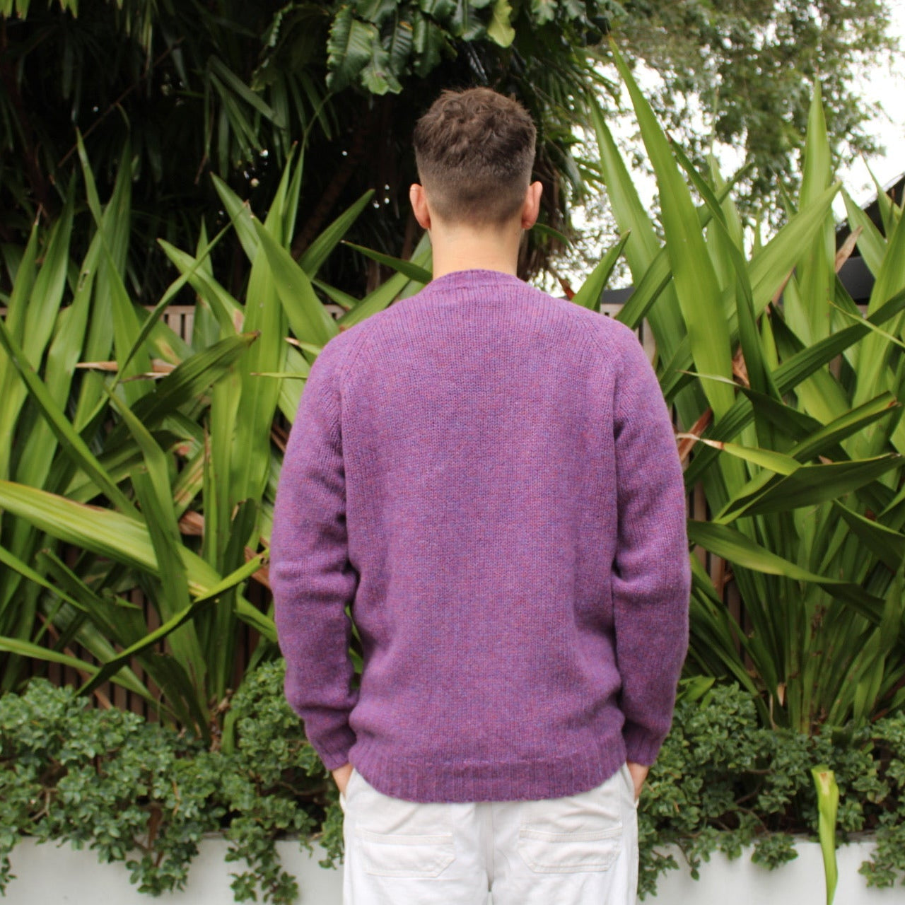 Man wearing the Chunky Crew neck wool Jumper in Calluna purple, back view
