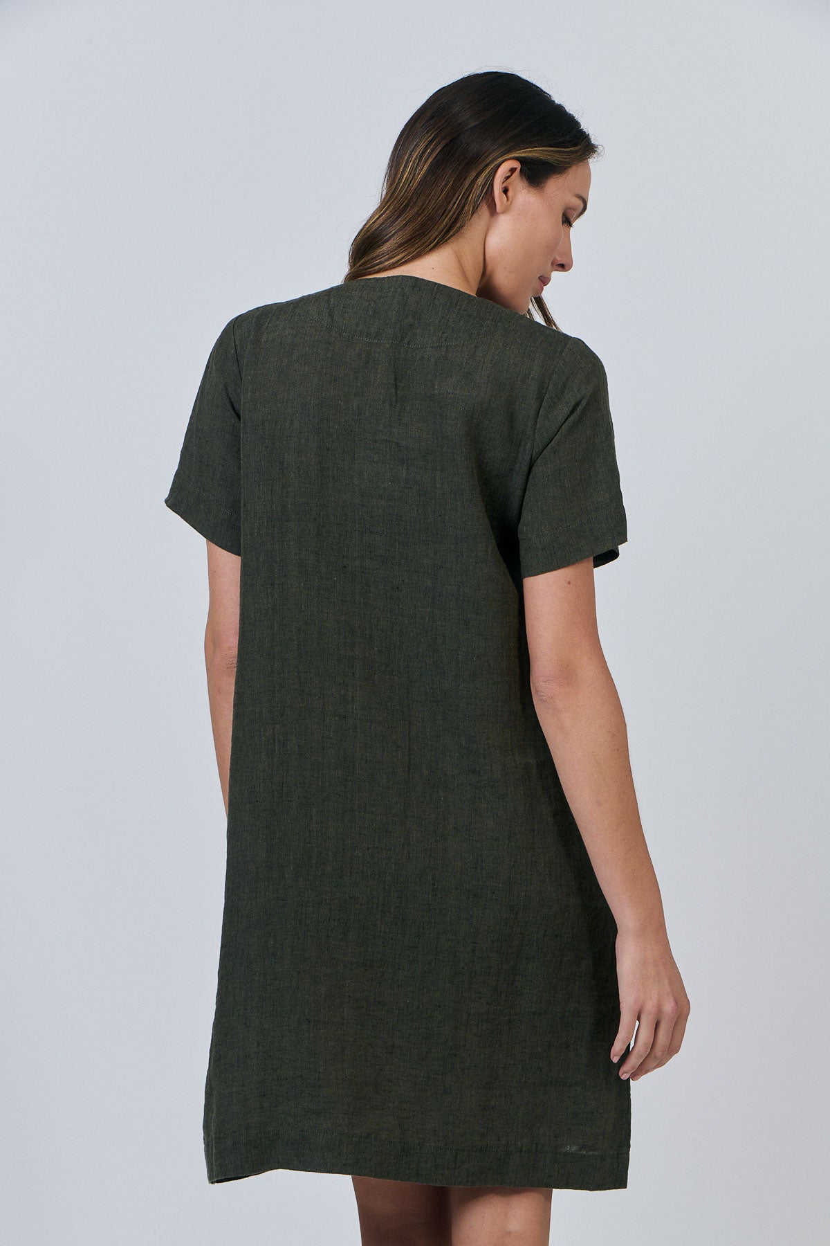 Woman wearing Naturals by O&J's Vee Stitch Linen Dress in Licorice green