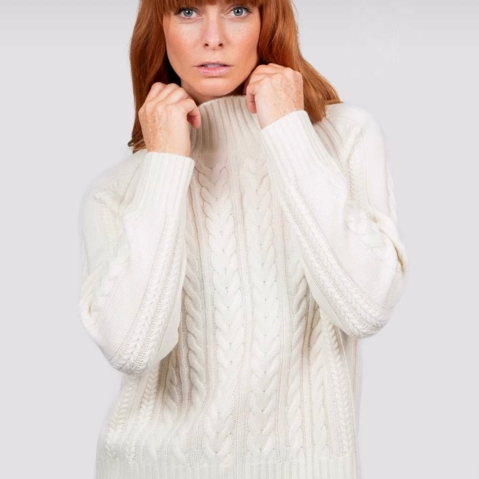 Woman wearing a white cabled knit jumper by Bridge and Lord
