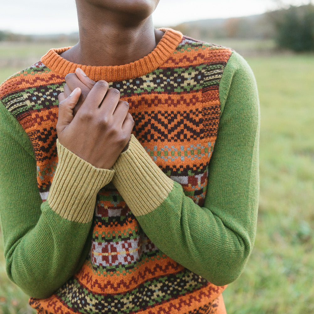 Eribe Stobo jumper worn on a model. Green and Orange Fairisle design with plain sleeves