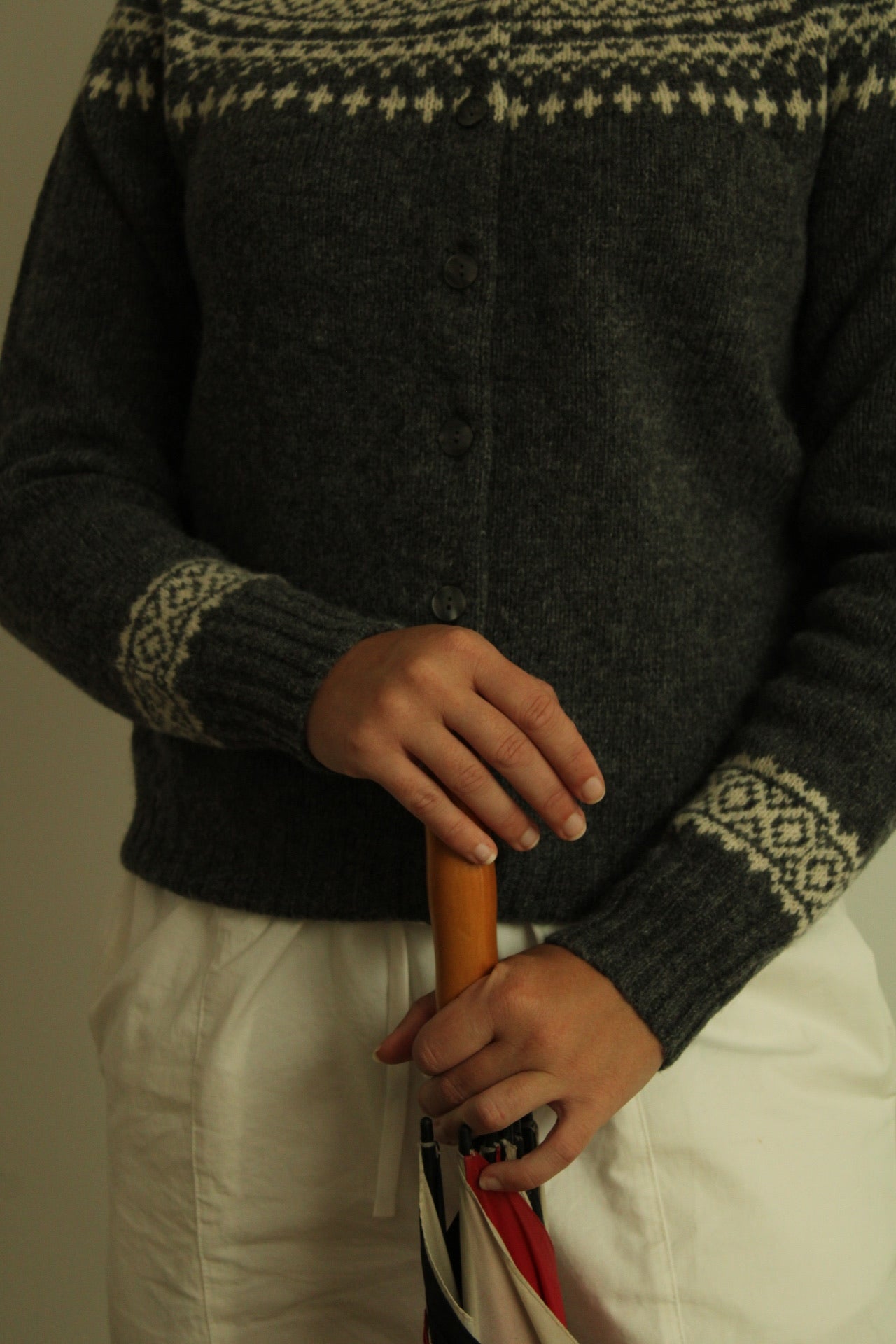 Woman wearing the Harley of Scotland Women's Fairisle Cardigan in Grey and white