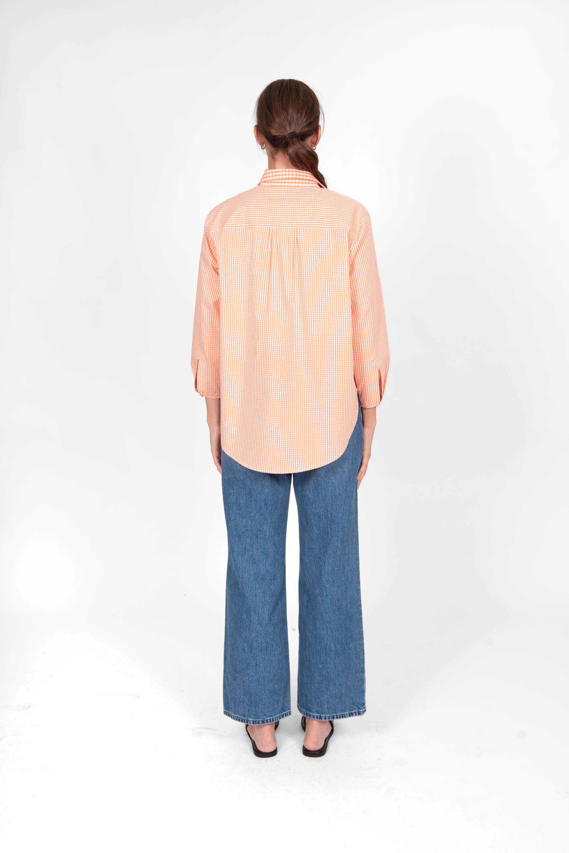 Woman wearing the Bridge and Lord Gingham cotton shirt in Clementine orange