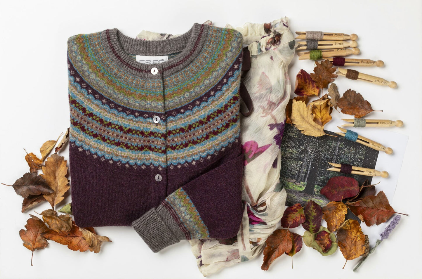 Eribe's Alpine cardigan in potpourri in an autumnal scene with leaves and woollen yarn